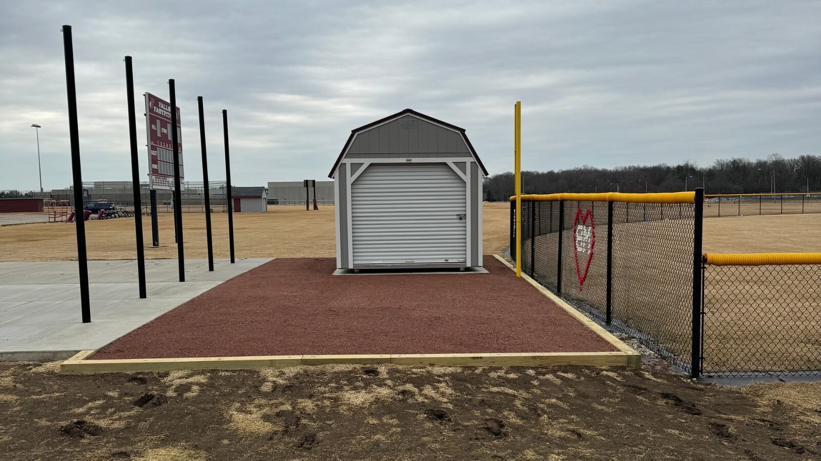 The integrated batting cage setup, complete with concrete pad, shed, and surrounding access.