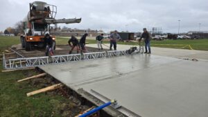 Our expert crew in action, pouring and screeding the concrete for a perfectly level batting cage foundation.