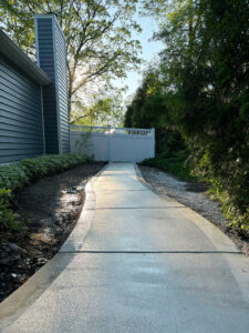 A view of a newly poured concrete walkway with a picture frame border, leading down a path at a home in New Berlin, WI.