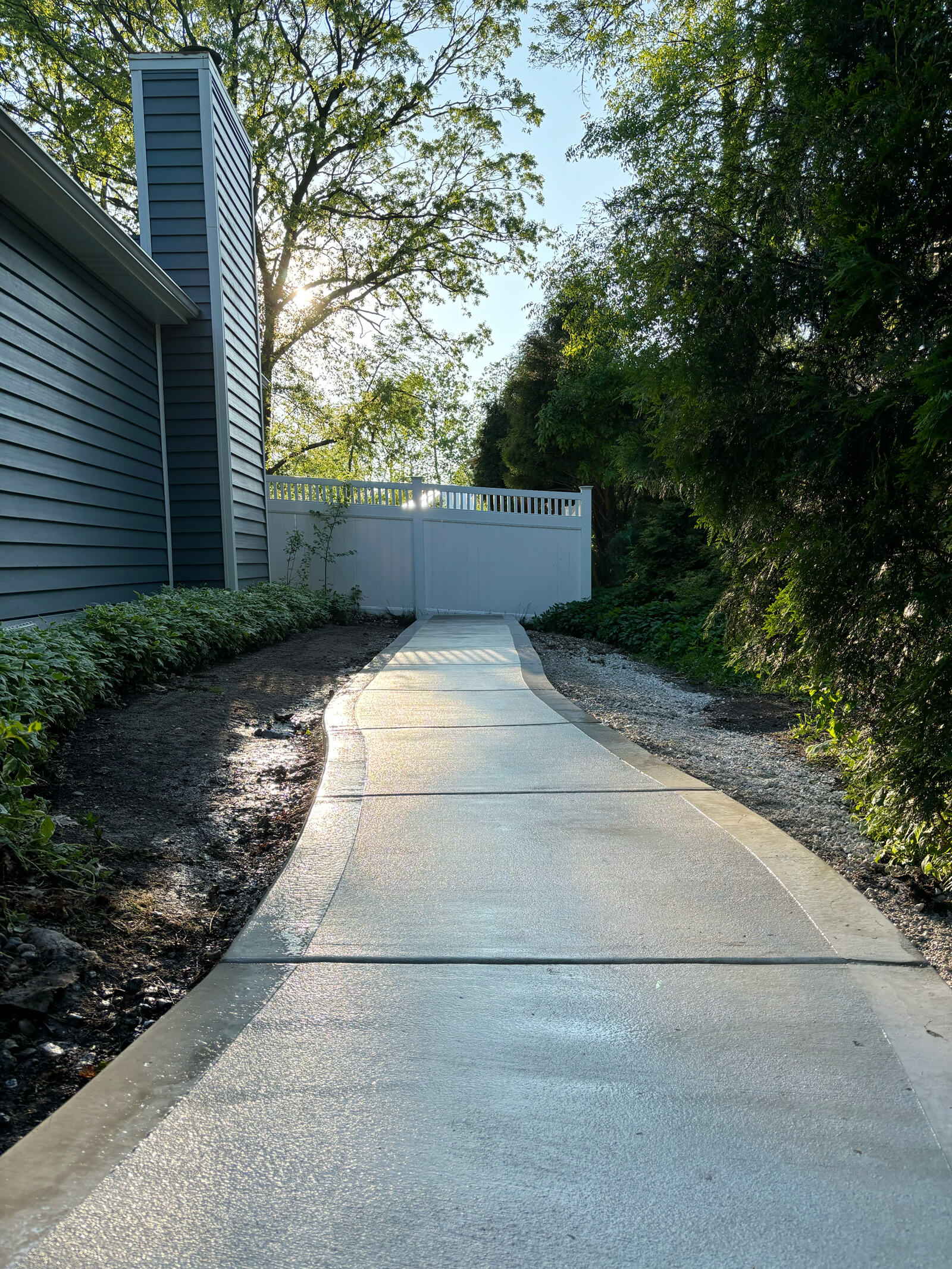 A view of a newly poured concrete walkway with a picture frame border, leading down a path at a home in New Berlin, WI.