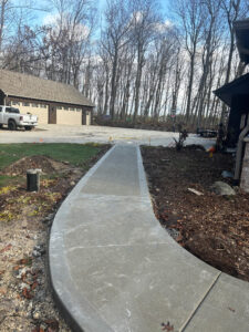 A view of the new concrete walkway with a picture frame border leading towards a garage on a residential property.