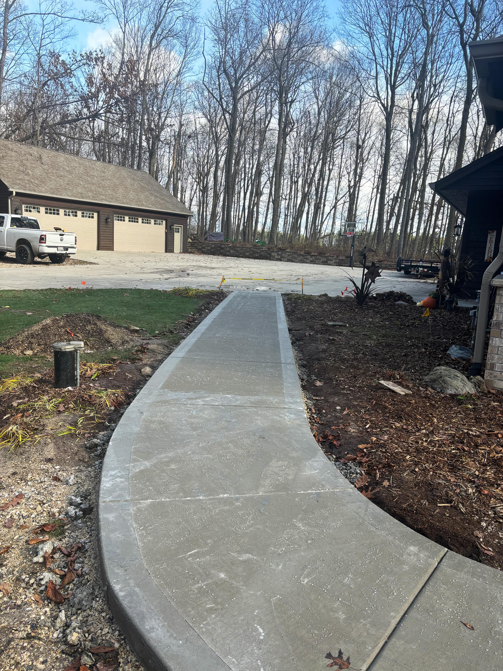 A view of the new concrete walkway with a picture frame border leading towards a garage on a residential property.