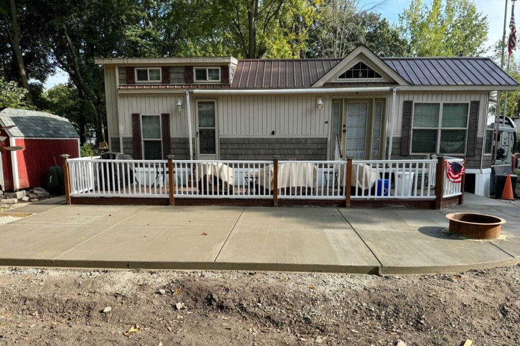 A newly poured concrete patio with a large planter box and a railing system at a home in Riverbend Resort, Watertown, WI, by Concrete Landscape Solutions.