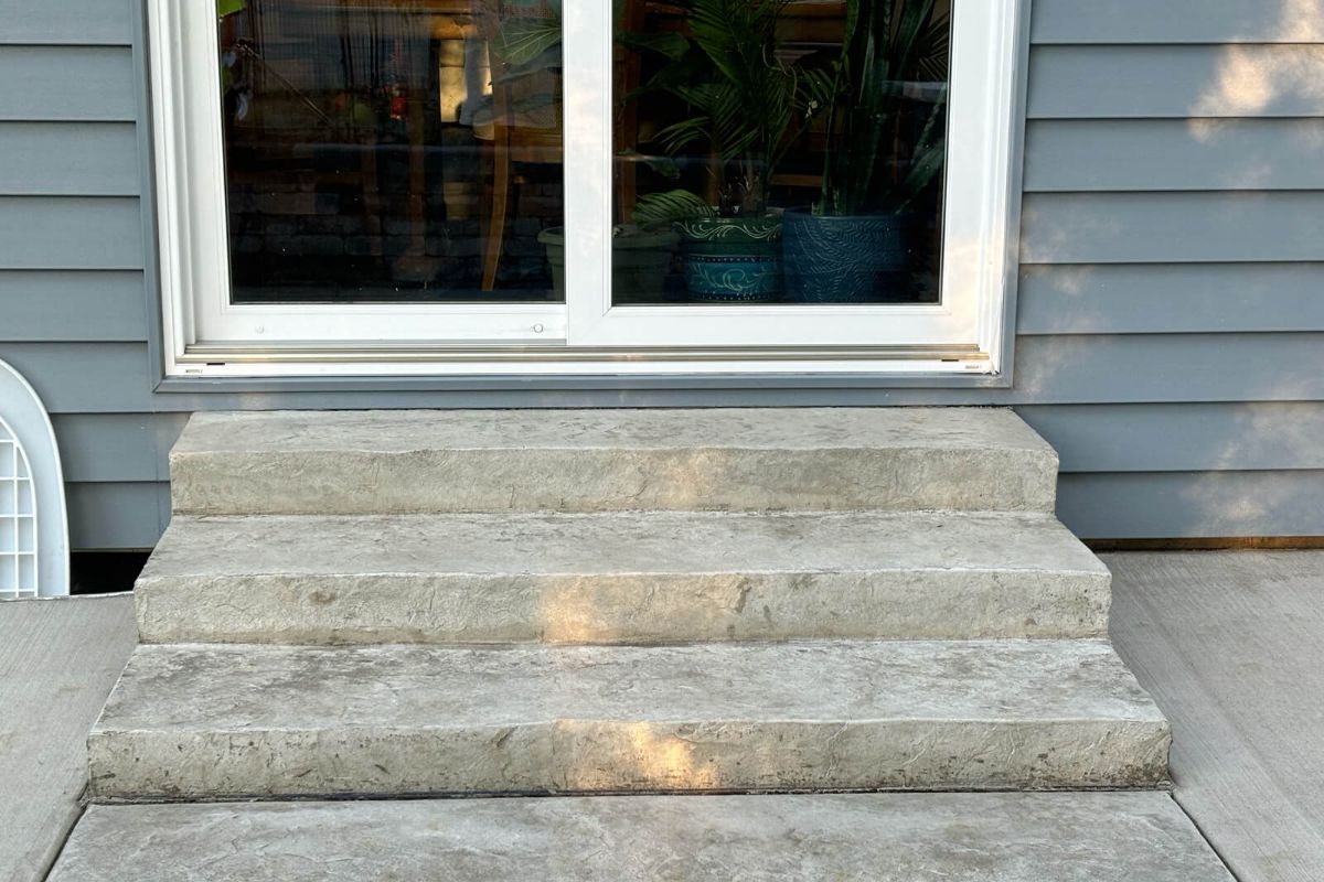 A new set of stamped concrete steps with a textured surface, leading up to a sliding glass door on a home in New Berlin, WI.