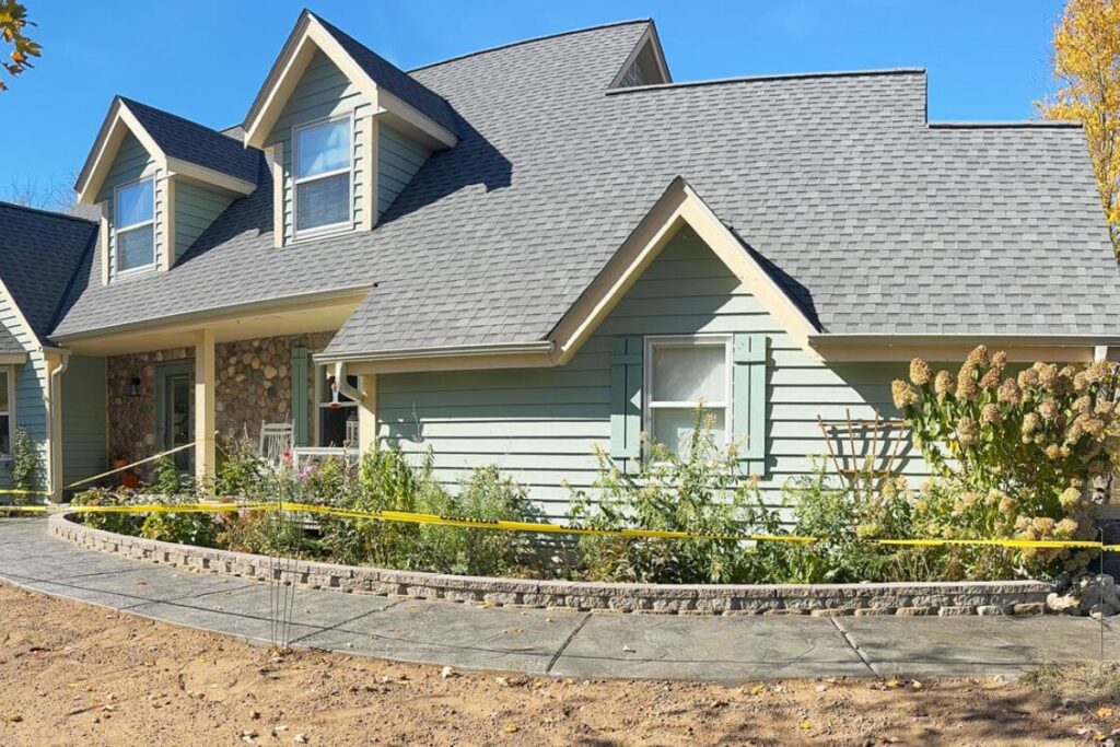 A newly installed curved stamped concrete walkway with a small retaining wall, leading to a home in Jackson, WI.