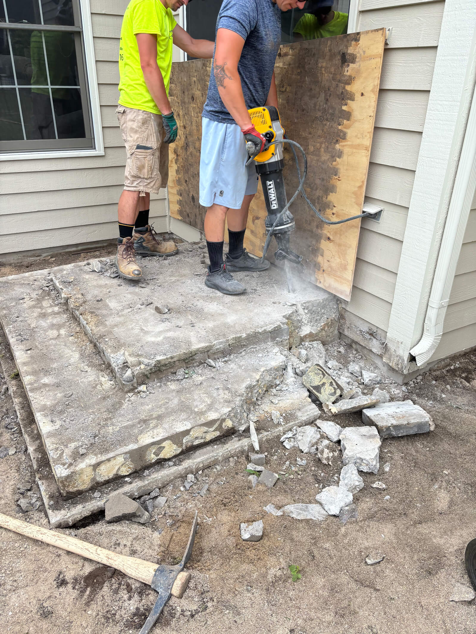 A crew using a jackhammer to remove an old concrete stoop at a home in Franklin, Wisconsin.