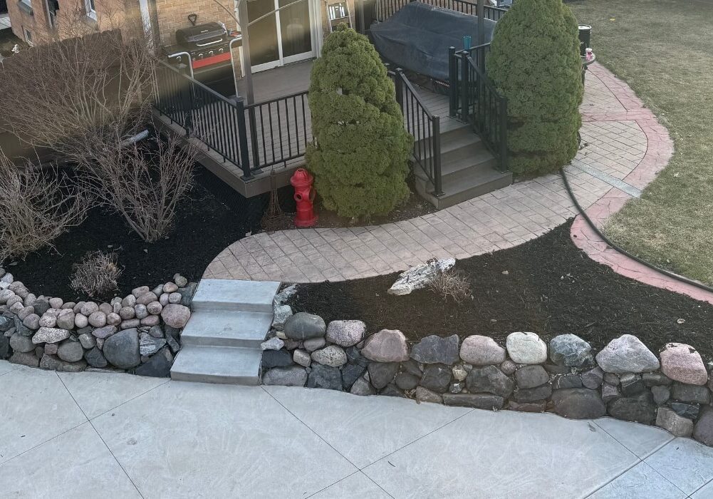 A backyard with a stone wall and a small garden showcasing hardscaping elements.